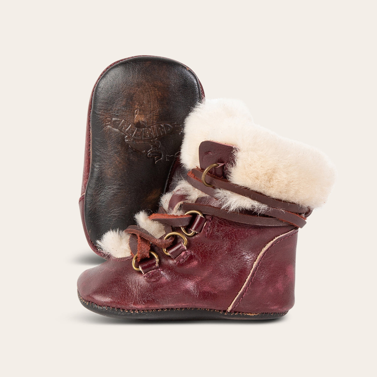 Side view showing shearling lining and contrasting leather lace detailing and soft leather imprinted sole on FREEBIRD infant baby Norway wine leather bootie